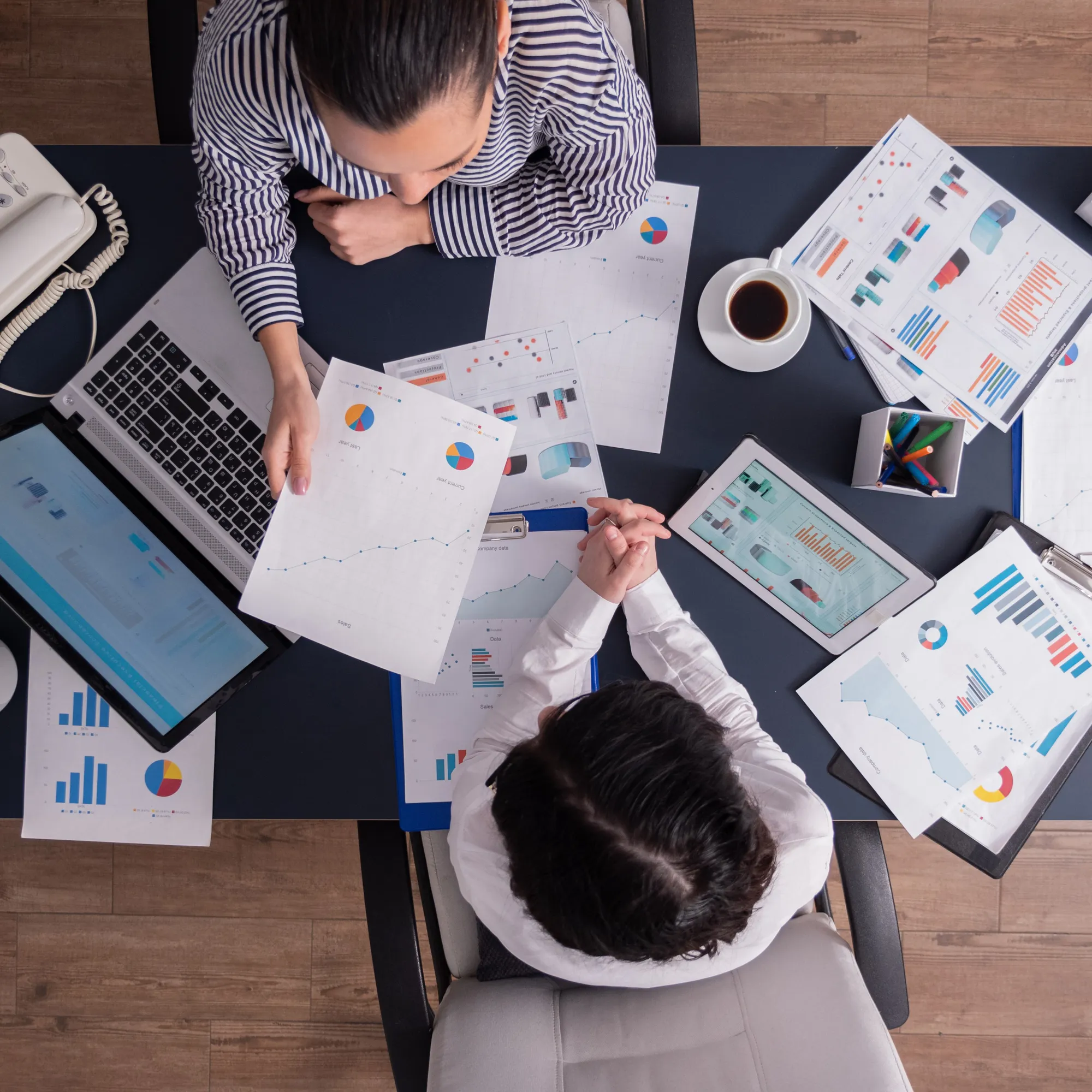 top-view-office-workers-meeting-analyzing-financial-charts-holding-clipboard